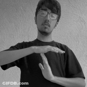 A Young Man Wearing Glasses And A Black Shirt Is Making A Gesture With His Hands . GIF