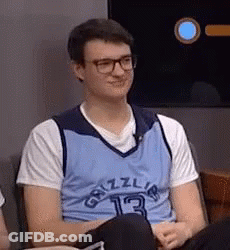 A Young Man Wearing Glasses And A Blue Grizzlies Jersey Is Sitting In A Chair . GIF