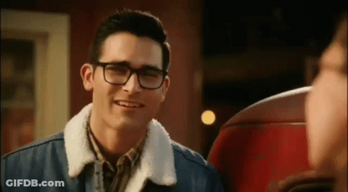 A Young Man Wearing Glasses And A Denim Jacket Is Smiling . GIF