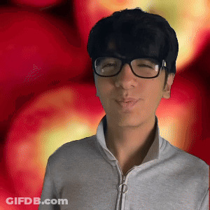 A Young Man Wearing Glasses And A Grey Jacket Stands In Front Of A Red Background GIF