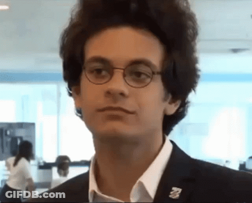 A Young Man Wearing Glasses And A Pin That Says ' A ' On It GIF