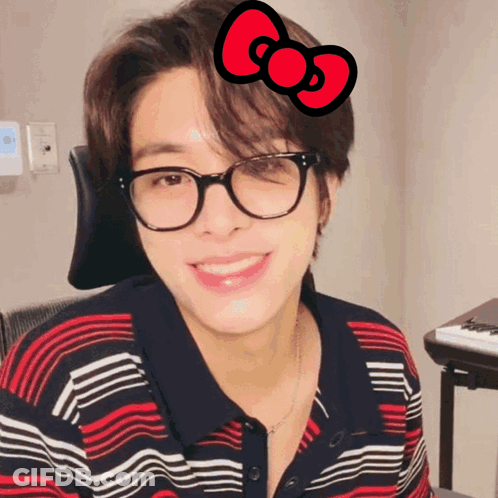 A Young Man Wearing Glasses And A Red Bow On His Head GIF