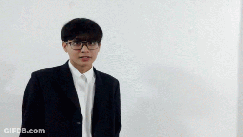 A Young Man Wearing Glasses And A Suit Is Making A Funny Face GIF