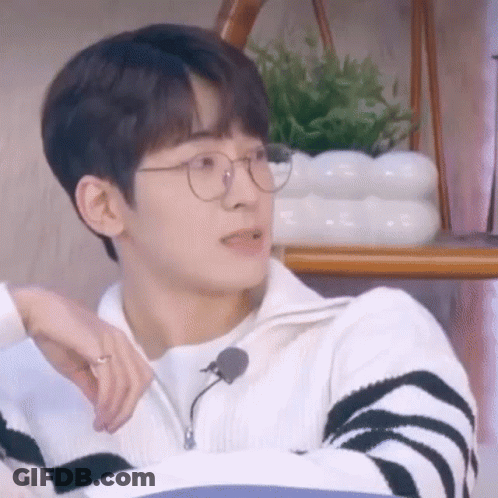 A Young Man Wearing Glasses And A Sweater Is Sitting On A Couch . GIF