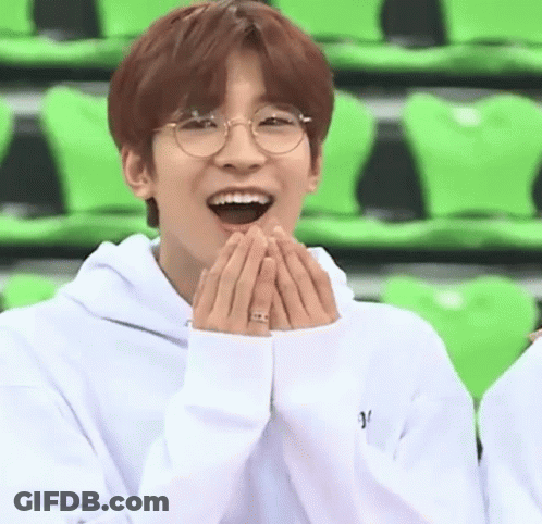 A Young Man Wearing Glasses And A White Hoodie Is Laughing With His Hands On His Face . GIF