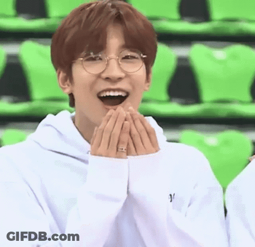 A Young Man Wearing Glasses And A White Hoodie Is Laughing . GIF