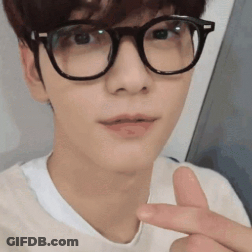 A Young Man Wearing Glasses And A White Shirt Is Making A Peace Sign . GIF