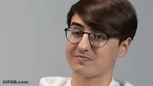 A Young Man Wearing Glasses And A White Shirt Is Making A Silly Face . GIF