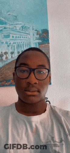 A Young Man Wearing Glasses And A White Shirt Stands In Front Of A Painting GIF