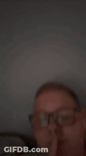 A Young Man Wearing Glasses And Earbuds Is Making A Funny Face GIF