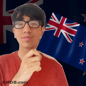A Young Man Wearing Glasses Holds A Small Flag In Front Of A British Flag GIF