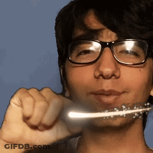 A Young Man Wearing Glasses Is Brushing His Teeth With A Toothbrush GIF