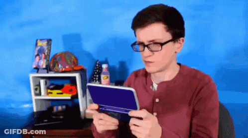 A Young Man Wearing Glasses Is Holding A Nintendo 3Ds GIF