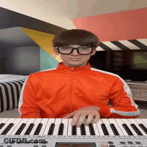 A Young Man Wearing Glasses Is Playing A Keyboard GIF