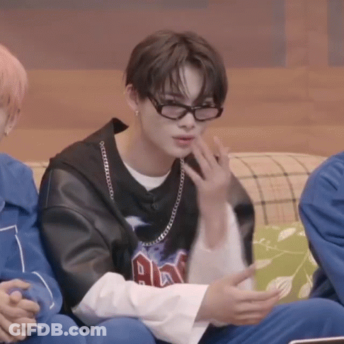 A Young Man Wearing Glasses Is Sitting On A Couch With Other People . GIF
