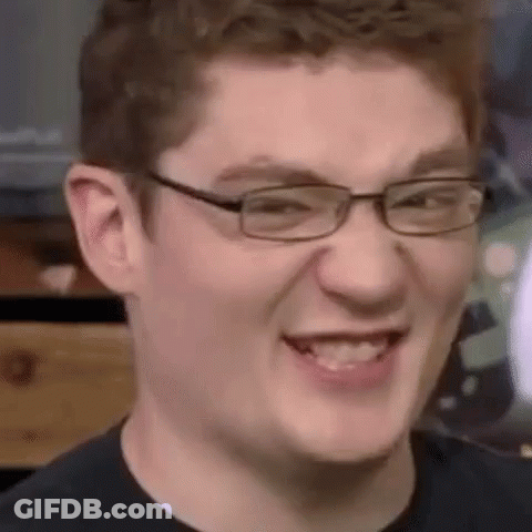 A Young Man Wearing Glasses Is Smiling And Making A Face . GIF