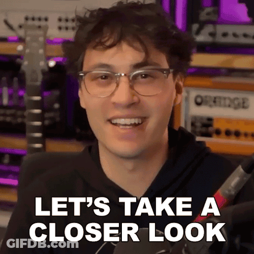 A Young Man Wearing Glasses Is Smiling And Says Let 'S Take A Closer Look GIF