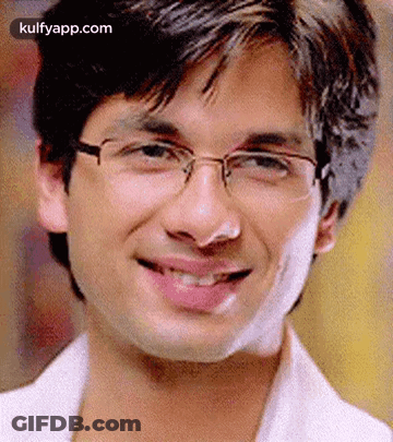 A Young Man Wearing Glasses Is Smiling For The Camera . GIF
