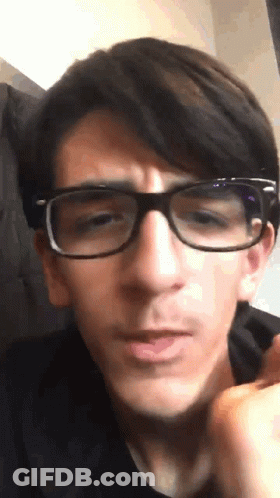 A Young Man Wearing Glasses Looks At The Camera GIF