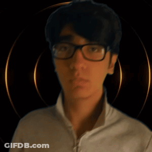 A Young Man Wearing Glasses Looks At The Camera GIF