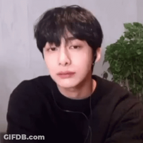 A Young Man Wearing Headphones And A Black Shirt Is Looking At The Camera . GIF