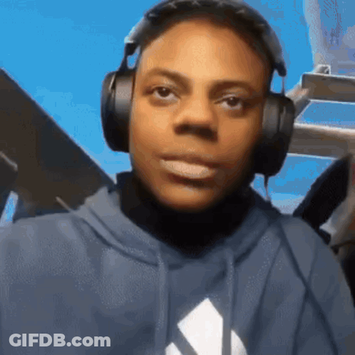 A Young Man Wearing Headphones And A Blue Hoodie Is Making A Funny Face . GIF