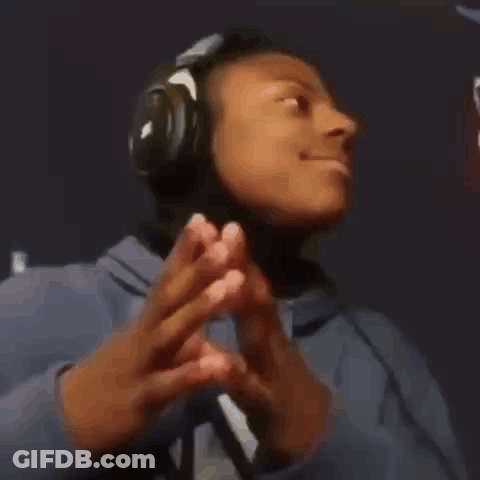 A Young Man Wearing Headphones And A Blue Hoodie Is Making A Peace Sign . GIF