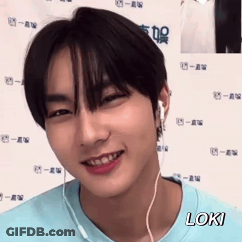 A Young Man Wearing Headphones And A Blue Shirt Is Smiling And Looking At The Camera . GIF