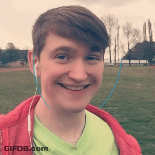 A Young Man Wearing Headphones And A Green Shirt Smiles GIF