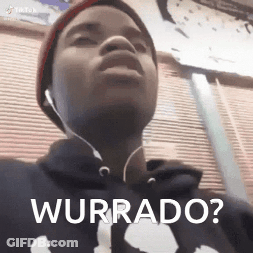 A Young Man Wearing Headphones And A Hat Is Making A Funny Face And Says Wurrado . GIF