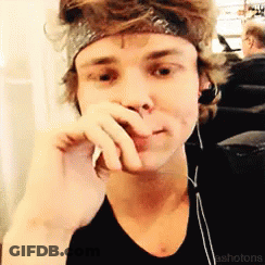 A Young Man Wearing Headphones And A Headband Is Covering His Mouth With His Hand GIF