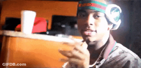 A Young Man Wearing Headphones And A Headband Is Smoking A Cigarette And Sticking His Tongue Out . GIF