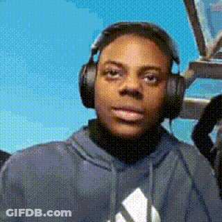 A Young Man Wearing Headphones And A Hoodie Is Looking At The Camera . GIF