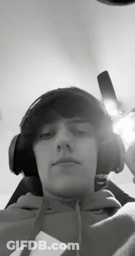 A Young Man Wearing Headphones And A Hoodie Is Taking A Selfie . GIF