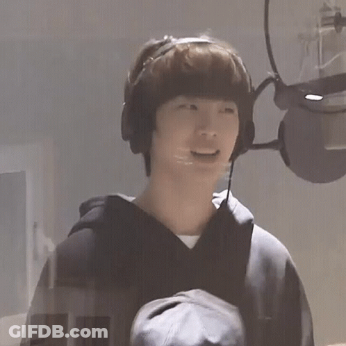 A Young Man Wearing Headphones And A Microphone Is Laughing . GIF