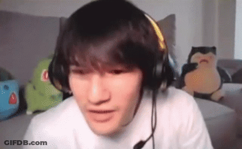 A Young Man Wearing Headphones And A Microphone Is Sitting On A Couch In A Living Room . GIF