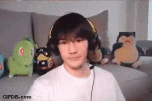 A Young Man Wearing Headphones And A Microphone Is Sitting On A Couch . GIF