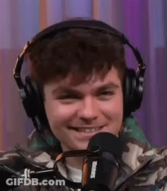 A Young Man Wearing Headphones And A Microphone Is Smiling . GIF