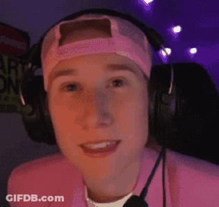 A Young Man Wearing Headphones And A Pink Hat Is Smiling . GIF