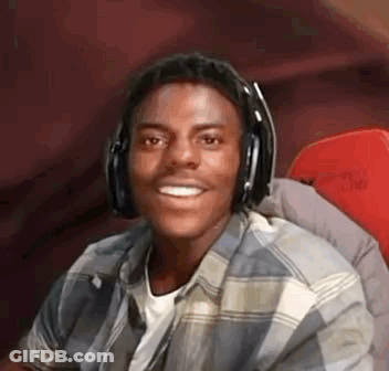 A Young Man Wearing Headphones And A Plaid Shirt Is Smiling While Sitting In A Chair . GIF