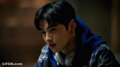 A Young Man Wearing Headphones And A Plaid Shirt Looks Down GIF