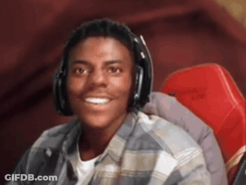 A Young Man Wearing Headphones And A Plaid Shirt Smiles For The Camera GIF