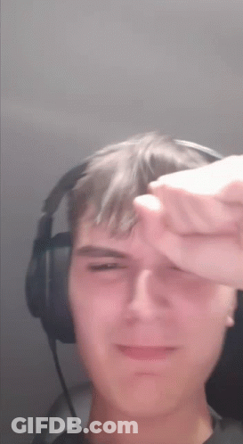 A Young Man Wearing Headphones Is Covering His Face With His Hand GIF