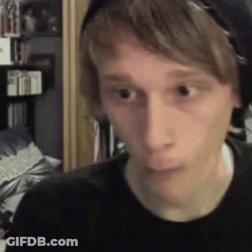 A Young Man Wearing Headphones Is Making A Funny Face While Looking At The Camera . GIF