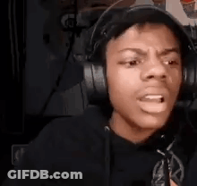 A Young Man Wearing Headphones Is Making A Funny Face While Sitting In Front Of A Microphone . GIF