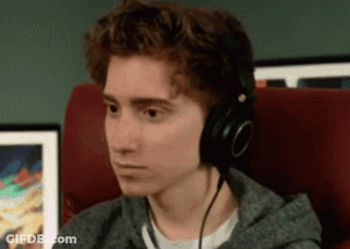 A Young Man Wearing Headphones Is Sitting In A Chair Looking At Something . GIF