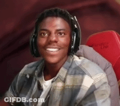 A Young Man Wearing Headphones Is Smiling And Sitting In A Red Chair . GIF