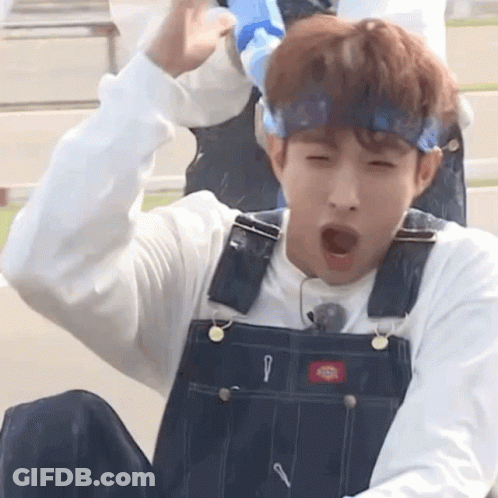 A Young Man Wearing Overalls And A Headband Is Yawning While Sitting Down . GIF