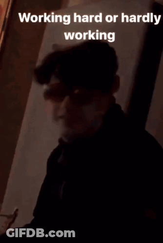 A Young Man Wearing Sunglasses And A Black Jacket Is Sitting In Front Of A Wall . GIF
