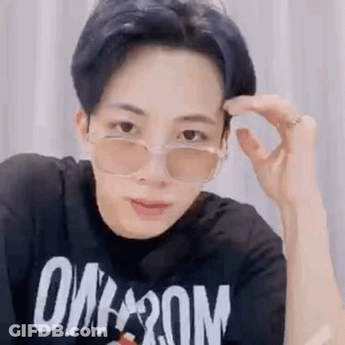 A Young Man Wearing Sunglasses And A Black T-Shirt Is Adjusting His Glasses . GIF